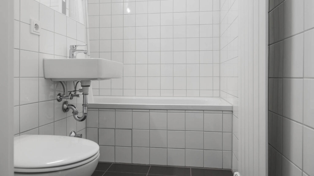 Older bathroom with sink, bathtub, and dark tiled floor in an apartment in Munich-Laim