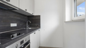 Kitchenette with dark countertop, hob, and window in an apartment in Munich-Laim