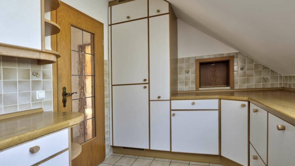 Küche des Hauses in Lochhausen mit weißen Fronten, Holztür und Dachschräge