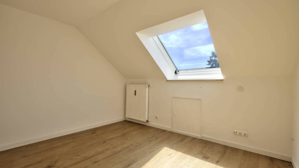 Leeres Zimmer des Hauses in Lochhausen mit Dachfenster, Heizkörper und Holzboden