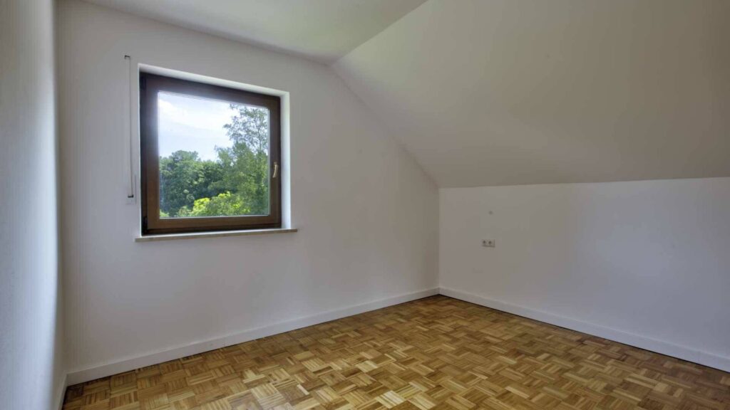 Leeres Zimmer des Hauses in Lochhausen mit Dachschräge, Fenster und Parkettboden