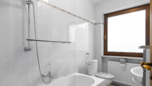 Weiß gefliestes Badezimmer mit Badewanne, Dusche und WC, renovierungsbedürftiger Zustand, Lochhausen