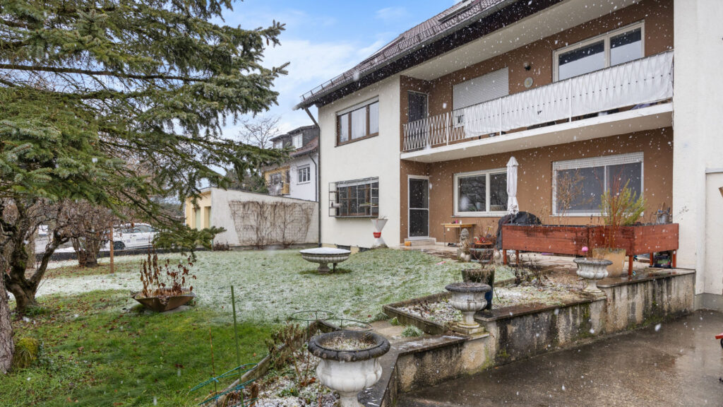 Rear view of the residential building with balcony and slightly snow-covered garden in Lochhausen