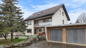 Weißes Mehrfamilienhaus mit Garagen und Kiefer, Außenansicht der Wohnanlage in Lochhausen