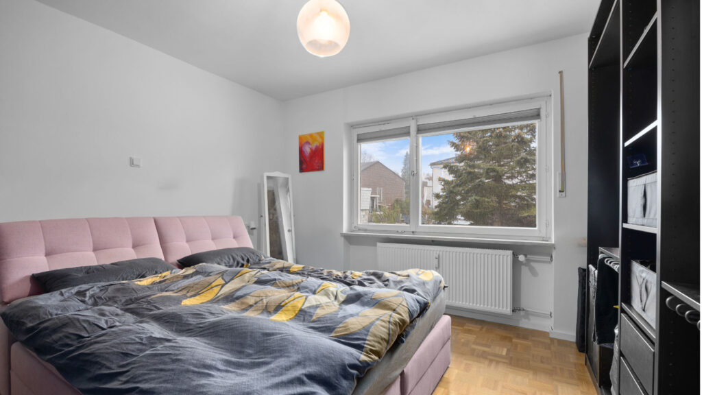 Bedroom in the apartment in Munich-Lochhausen with pink upholstered bed and black dresser