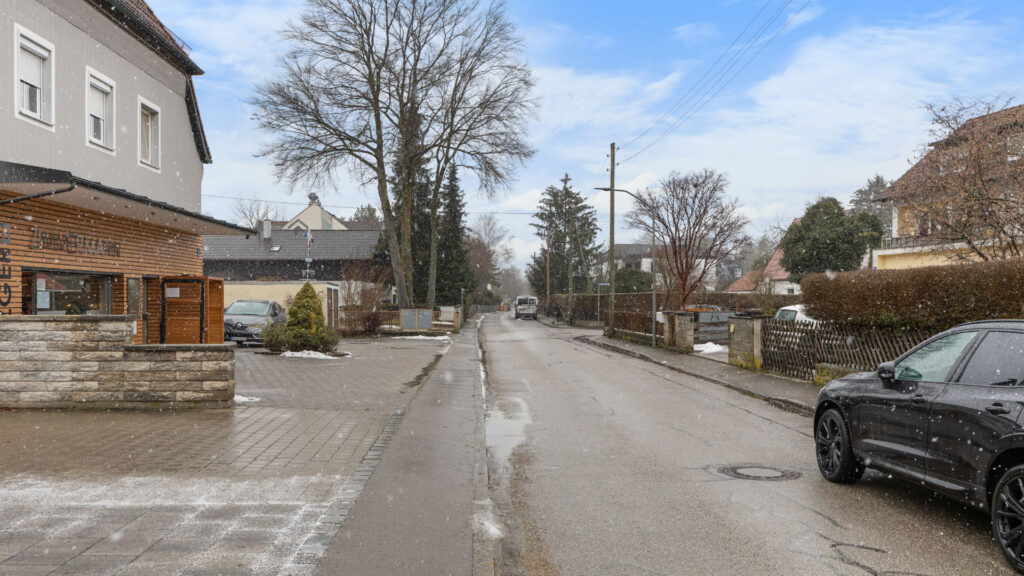 Street view in Munich-Lochhausen with a brick house and a wintery street