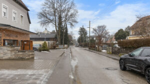 Straßenansicht in München-Lochhausen mit Backsteinhaus und winterlicher Straße