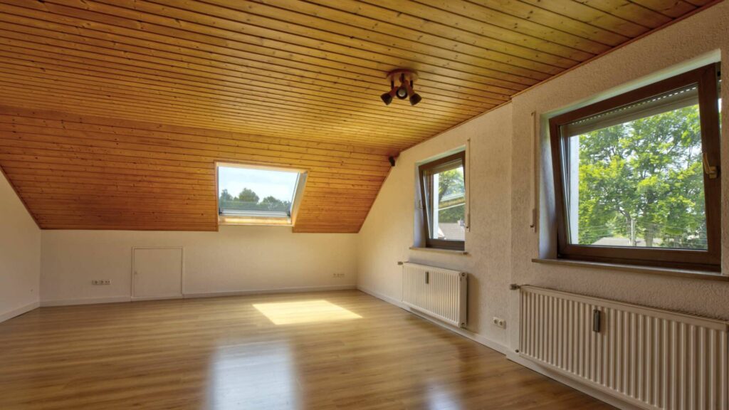 Unmöbliertes Zimmer unterm Dach des Hauses in Lochhausen mit Holzverkleidung und Fensterausblick