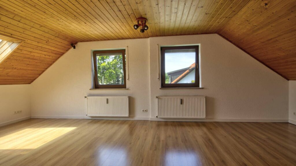 Leeres Wohnzimmer des Hauses in Lochhausen mit Holzdecke, Dachfenster und Parkettboden