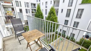 Balcony with wooden table, chairs and metal railing between residential buildings in Ludwigsvorstadt
