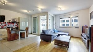 Living room with a blue couch, dining area, and parquet flooring in a Ludwigsvorstadt apartment