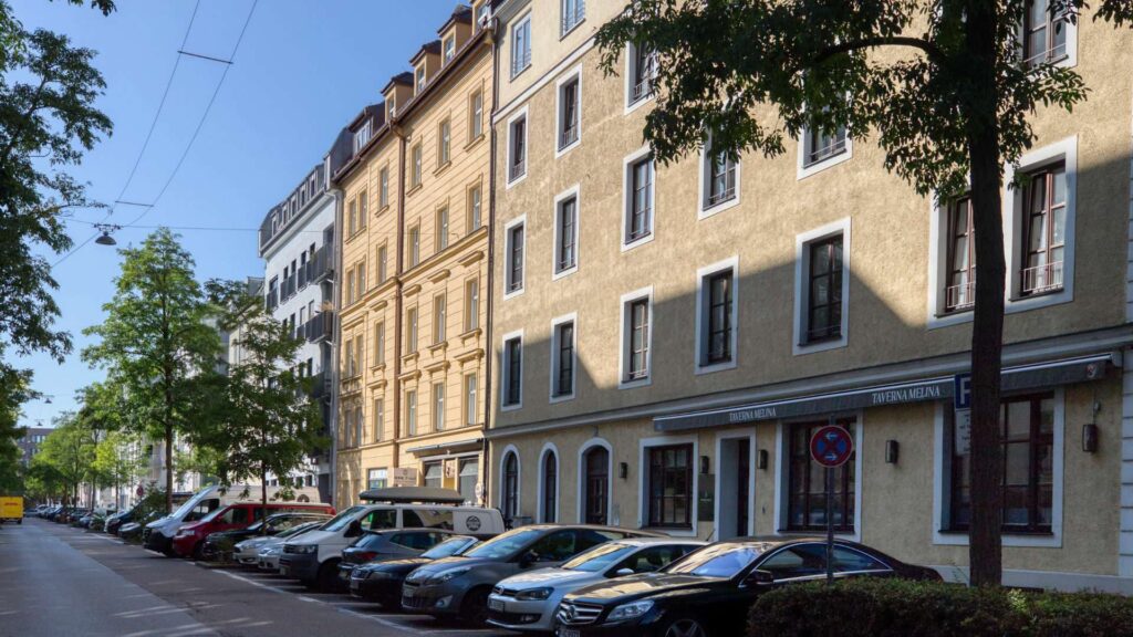 Altbaufassade mit Ladengeschäft in der Ludwigsvorstadt in München und parkenden Autos
