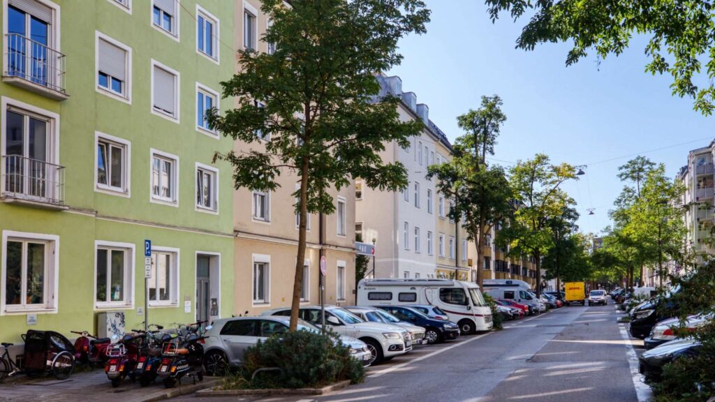 Straßenansicht in der Ludwigsvorstadt in München mit gelbgrüner Fassade und parkenden Autos