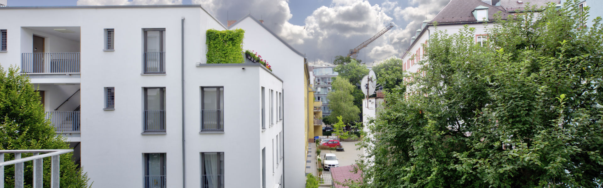 Residential street with a modern white new building and a historic church tower in Ludwigsvorstadt