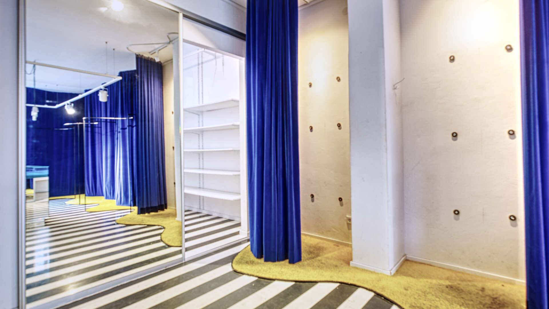 Elaborately designed fitting area with blue curtains and a striped pattern in a retail space in Munich's Maxvorstadt district