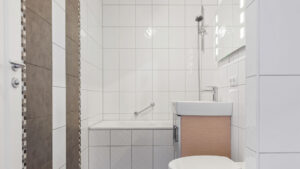 Badezimmer mit bodengleicher Dusche, Waschbecken und beigefarbenen Fliesen in einer Wohnung in München-Milbertshofen