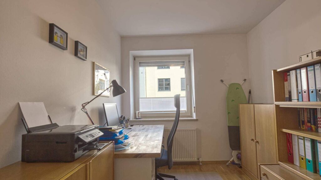 Living room of the apartment in Munich-Obersendling with desk by the window and bookcase