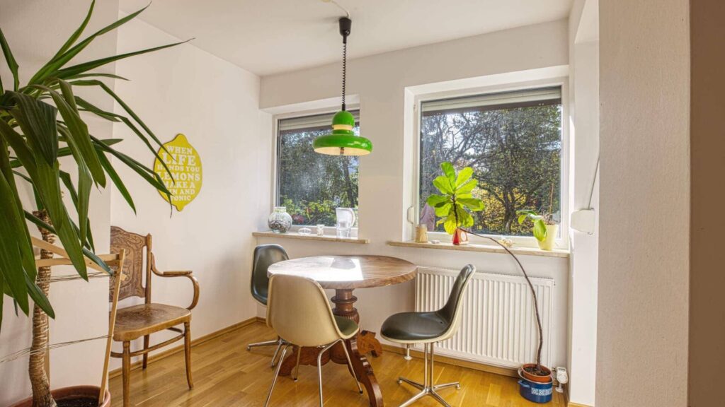 Living room in the Munich-Obersendling apartment with a round table, greenery, and a green pendant light