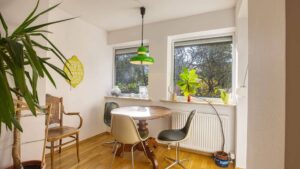 Living room in the Munich-Obersendling apartment with a round table, greenery, and a green pendant light