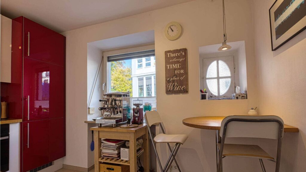 Dining area in the kitchen of the apartment in Munich-Obersendling with round table and red refrigerator