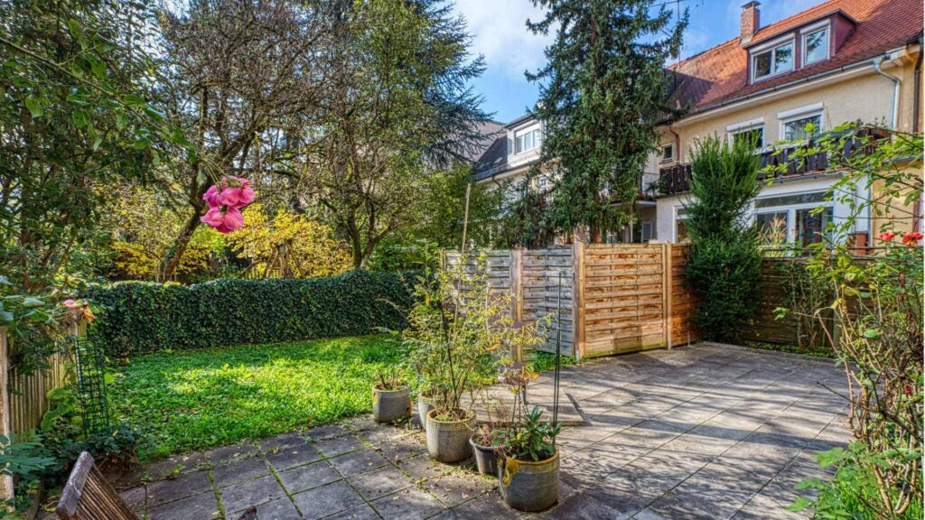 Garden of the apartment in Munich-Obersendling with a lawn area, hedge and wooden fence