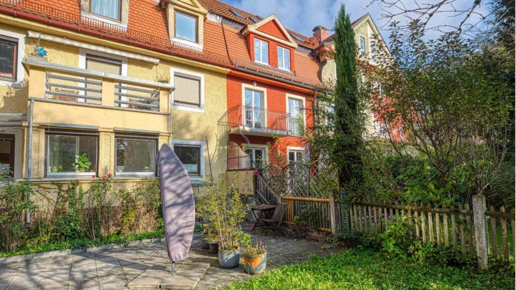 View of the house with the garden of the apartment in Munich-Obersendling with a yellow and red facade and terrace