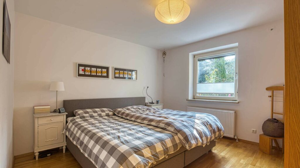 Bedroom in the Munich-Obersendling apartment with a double bed and a checkered bedspread