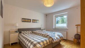 Bedroom in the Munich-Obersendling apartment with a double bed and a checkered bedspread