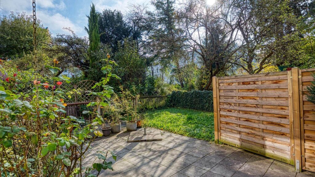 Terrace of the apartment in Munich-Obersendling with paved surface, wooden fence and greenery