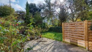 Terrace of the apartment in Munich-Obersendling with paved surface, wooden fence and greenery