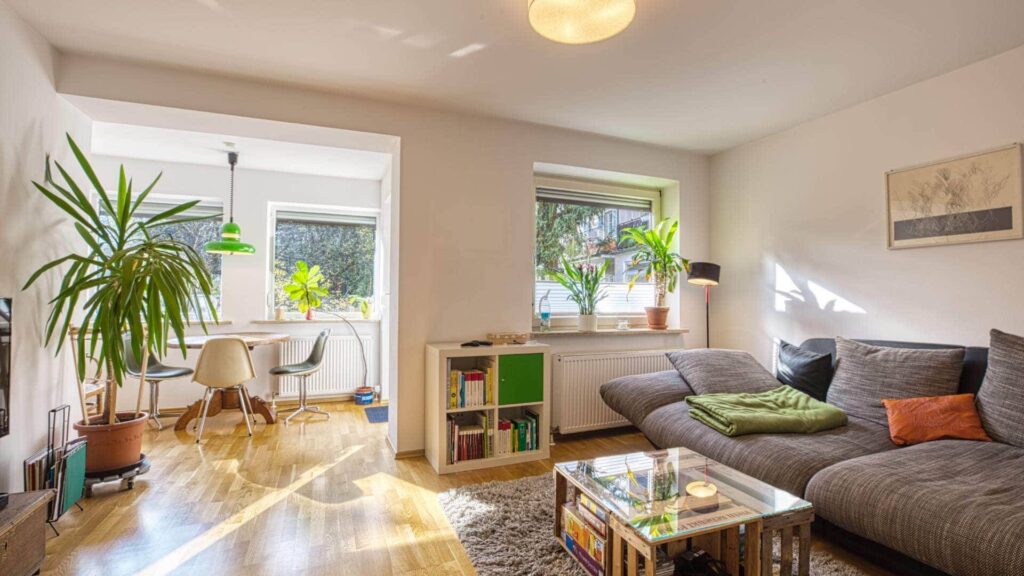 Living room of the apartment in Munich-Obersendling with a gray couch, dining table, and large windows