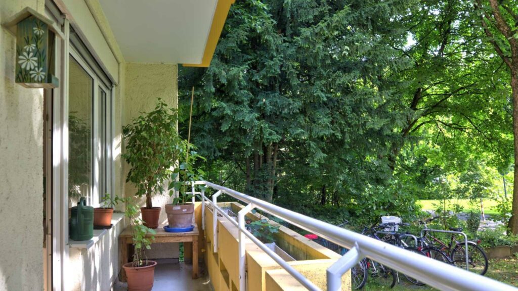 Balcony with potted plants and wooden railings, including parked bicycles and trees in Munich-Perlach