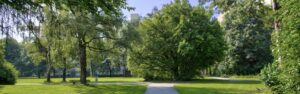 Narrow path through the park with trees surrounding the apartment in Perlach