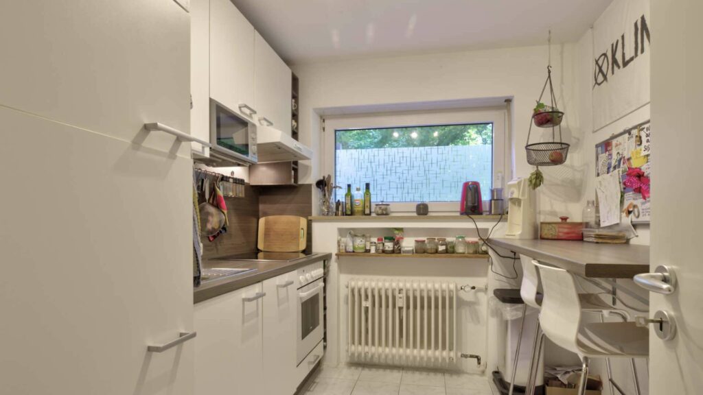 White built-in kitchen with windows, seating area and bar stools in the apartment in Munich-Perlach