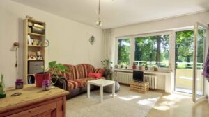 Living room with cozy seating area, bookcase, and balcony door overlooking a green area in Perlach