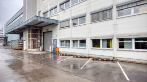Building entrance with canopy and marked parking spaces in Puchheim – Rogers Immobilien