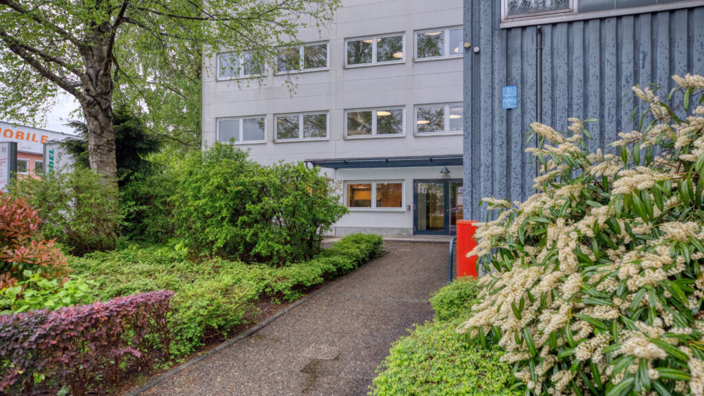 Garden path with flowering shrubs leading to the entrance of the office building in Puchheim – Rogers Real Estate