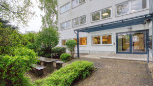 Courtyard with seating area and covered entrance of the office building in Puchheim – Rogers Immobilien