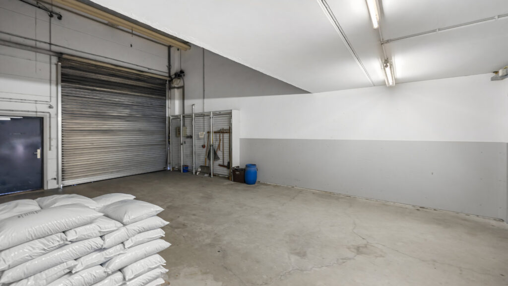 Delivery area with roller shutter and stacked goods in the Puchheim office building – Rogers Immobilien
