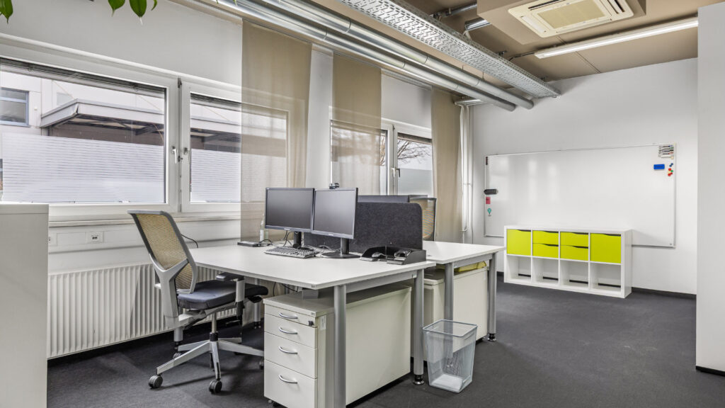 Workplace with two monitors and a yellow sideboard in the Puchheim office building – Rogers Real Estate