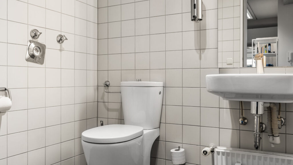 Men's restroom with white tiles and washbasin in the Puchheim office building – Rogers Immobilien