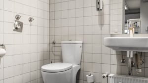 Men's restroom with white tiles and washbasin in the Puchheim office building – Rogers Immobilien