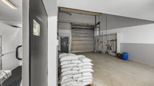 Delivery area with roller shutter and stacked bags in the Puchheim office building – Rogers Real Estate