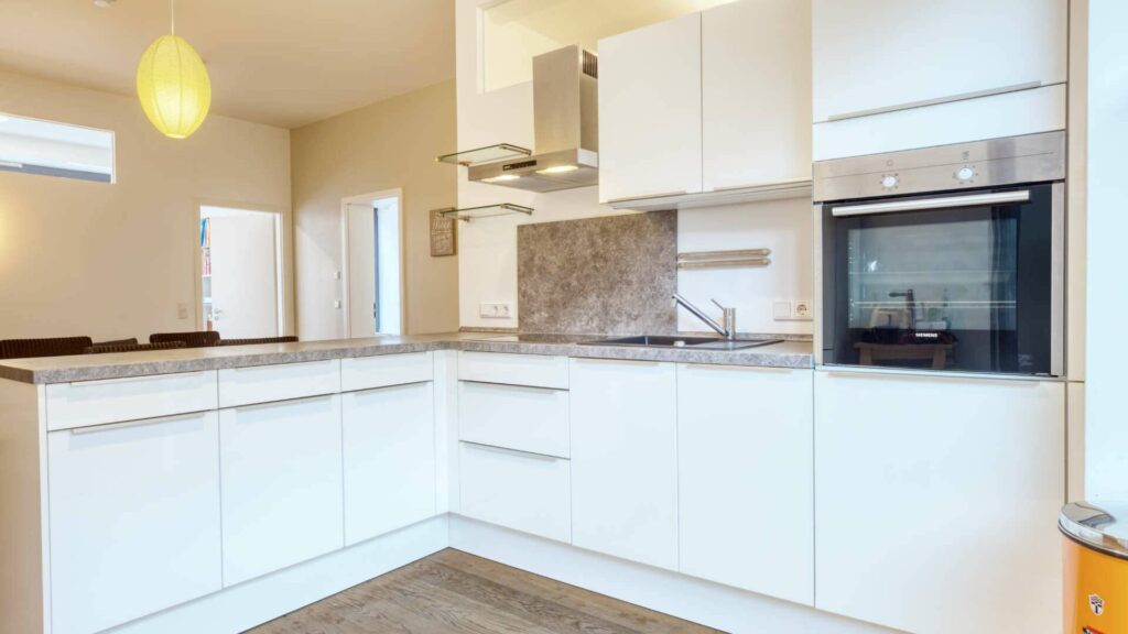 L-shaped fitted kitchen with granite worktop and light wooden floor in the apartment in Schwabing – Rogers Immobilien