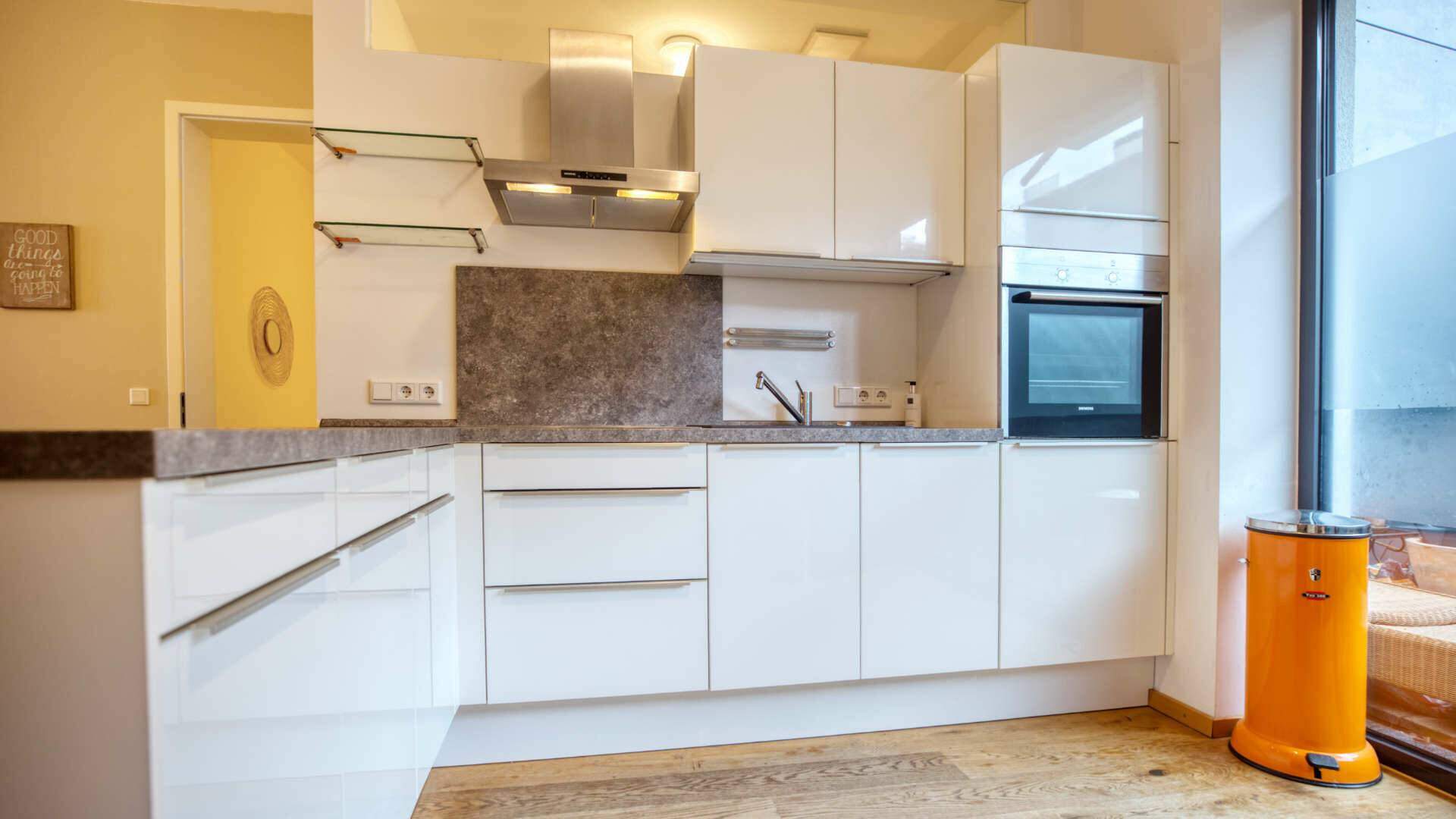Built-in kitchen with white high-gloss fronts and a view of the outside – apartment in Munich-Schwabing – Rogers Immobilien