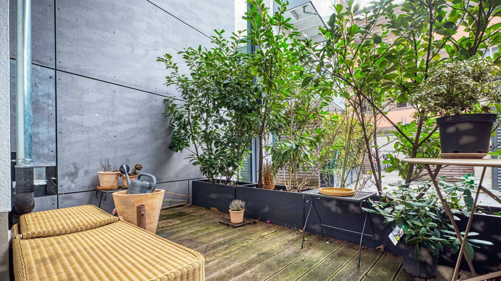 Roof terrace with striped sun lounger and plant beds in the apartment in Munich-Schwabing – Rogers Immobilien