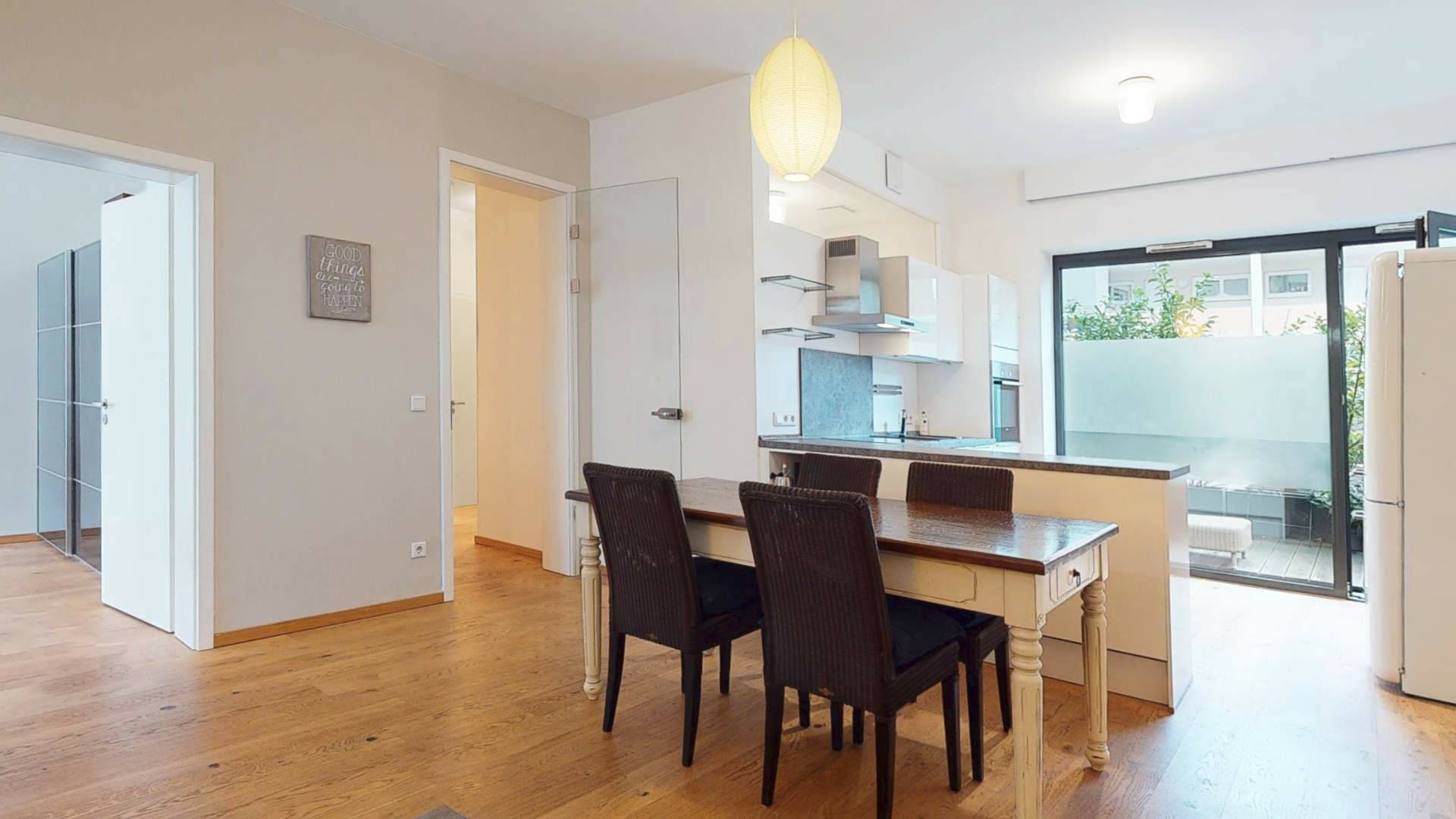 Dining area next to open kitchen with a view of the patio door in the Schwabing apartment – Rogers Immobilien