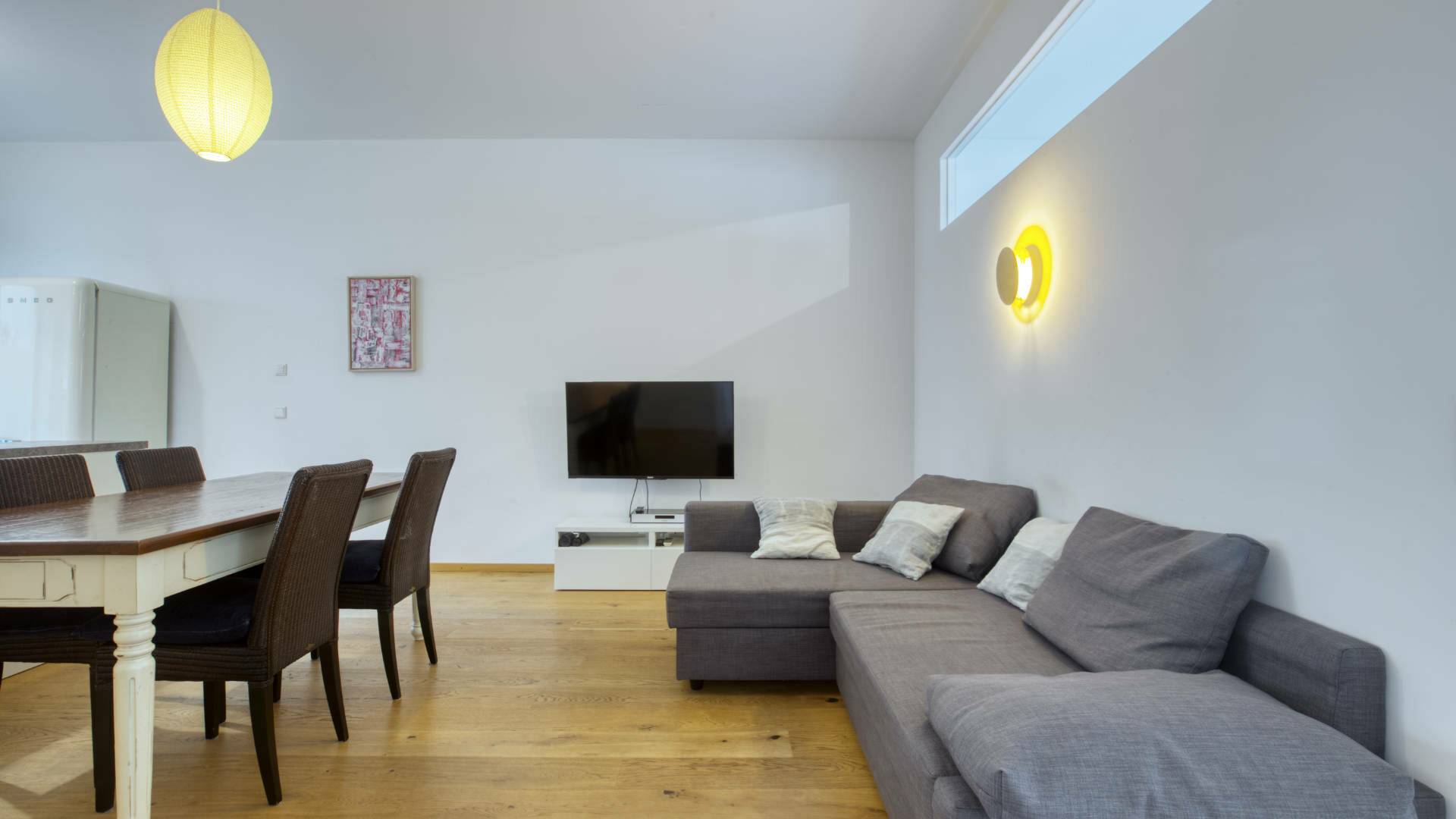 Living room with dining table, dark chairs and gray sofa in the apartment in Schwabing – Rogers Immobilien