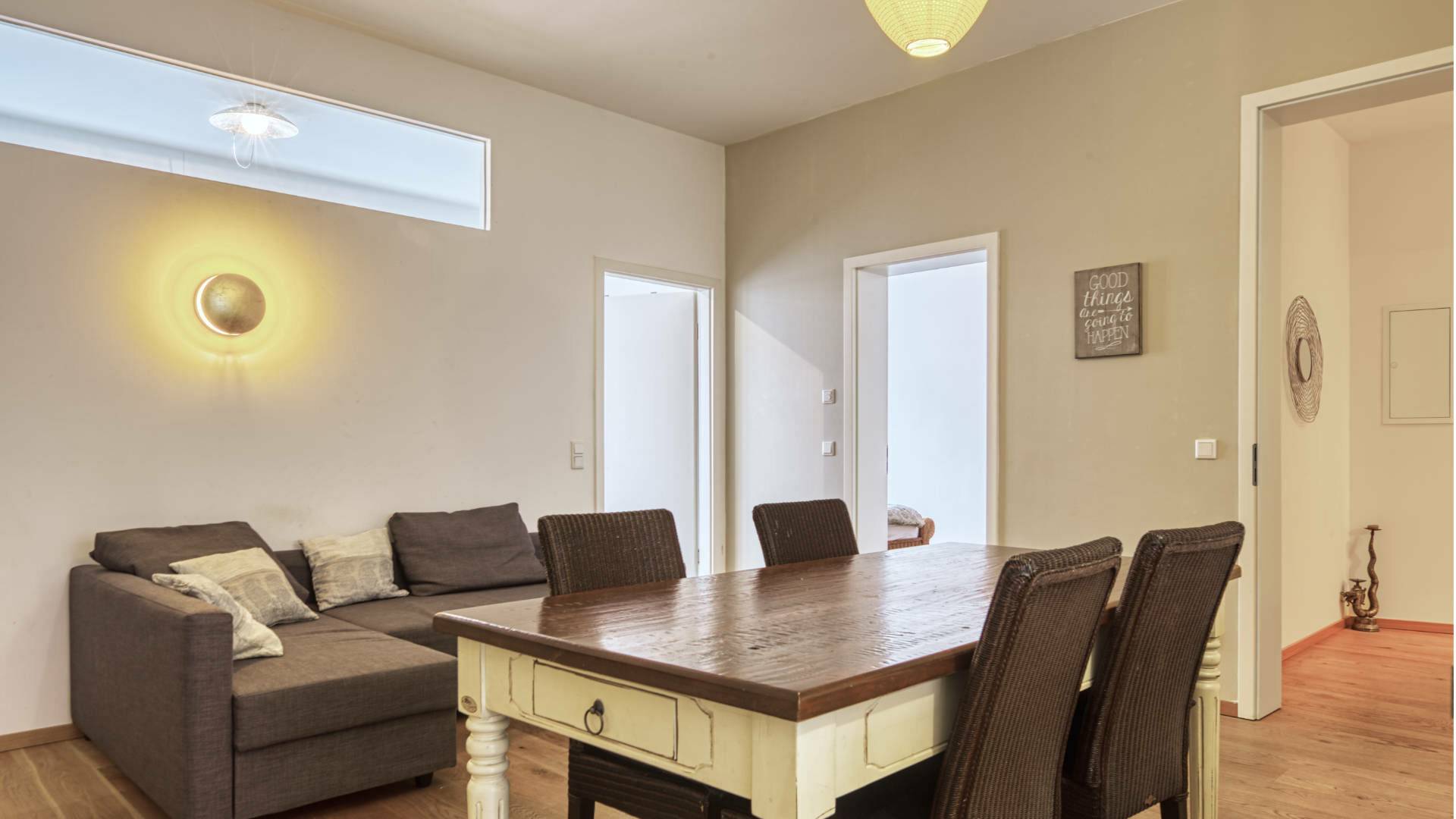 Dining area with dark wooden table and gray couch in the apartment in Schwabing – Rogers Immobilien