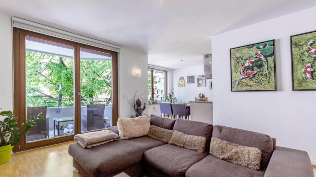 Wohnzimmer der Wohnung in Sendling mit brauner Couch, Terrassentür und Bildern an der Wand